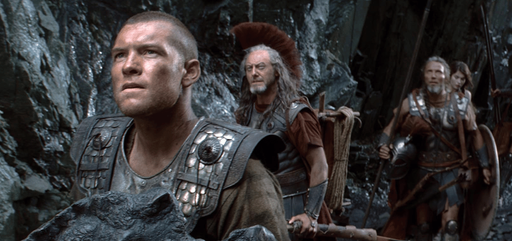 Beberapa prajurit berpakaian zirah logam berjalan di antara tebing batu dalam adegan film Clash of the Titans tahun 2010.