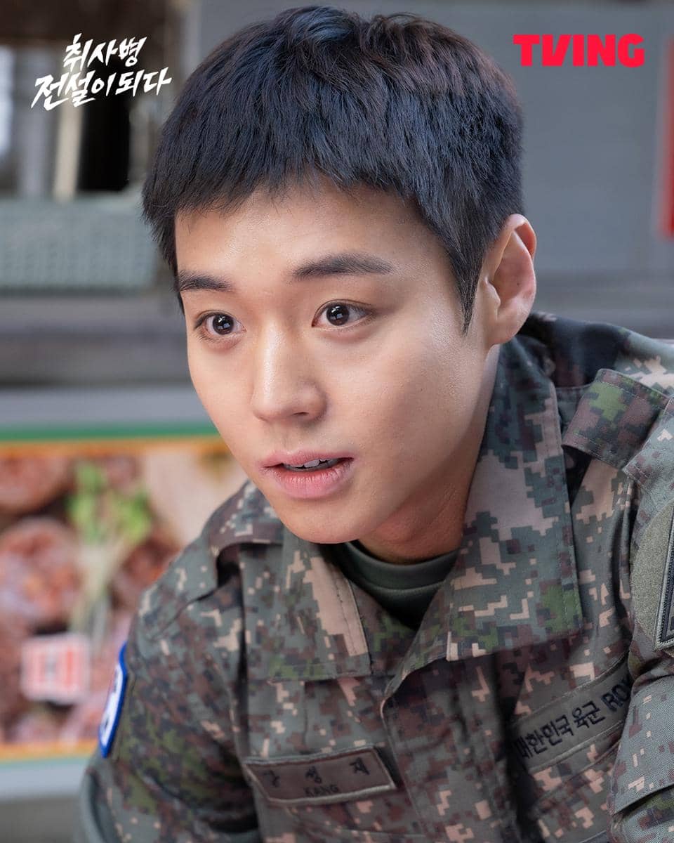 Seorang pria muda mengenakan seragam militer Korea dengan ekspresi serius dalam cuplikan drama The Legend of Kitchen Soldier.