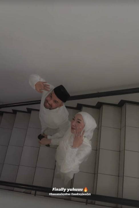Sepasang pengantin berpakaian putih tersenyum dan melambaikan tangan di tangga setelah melangsungkan akad nikah di KUA.