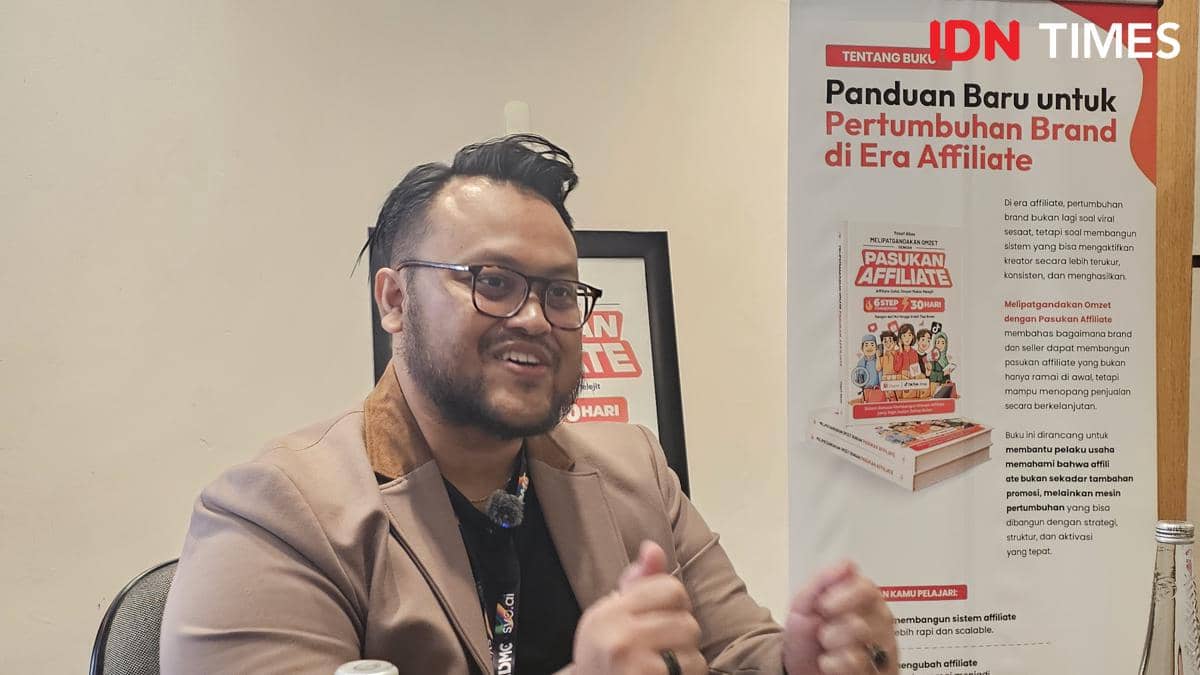 Seorang pria mengenakan jas cokelat dan kacamata sedang berbicara di acara peluncuran buku tentang strategi pertumbuhan brand di era affiliate di ICE BSD, Tangerang.