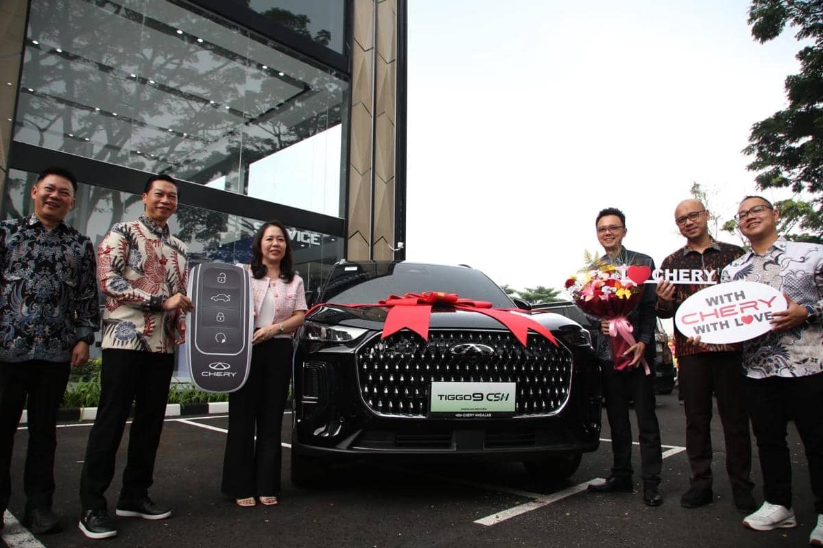 Beberapa orang berpose di depan mobil Chery Tiggo 9 CSH hitam dengan pita merah besar saat acara penyerahan unit kepada konsumen.