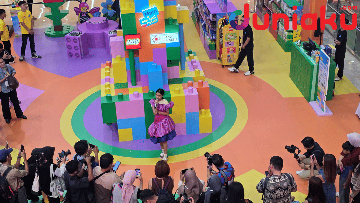 Seorang penyanyi tampil di area LEGO Playground berwarna cerah di Grand Indonesia, dikelilingi penonton dan fotografer.