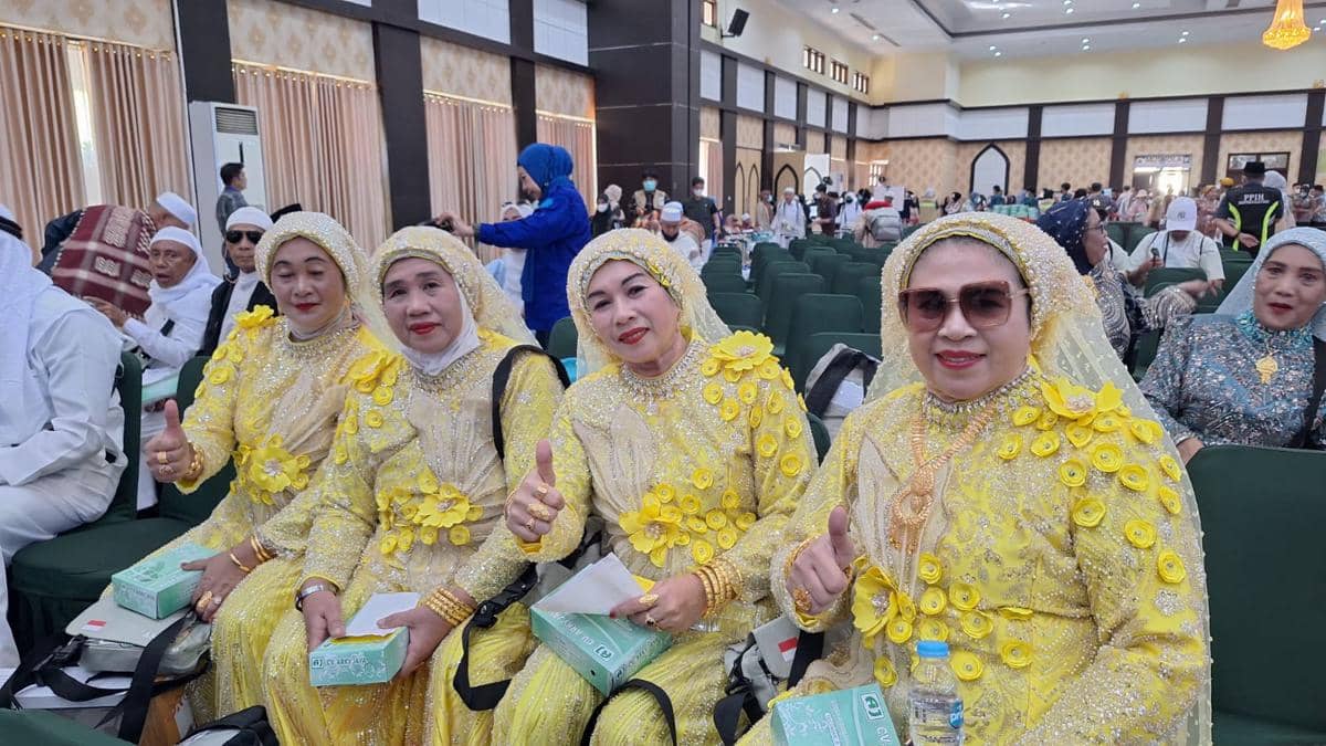 Empat jemaah haji Debarkasi Makassar Kloter 5 mengenakan busana kuning berhias payet dan bunga saat tiba di Asrama Haji Sudiang.