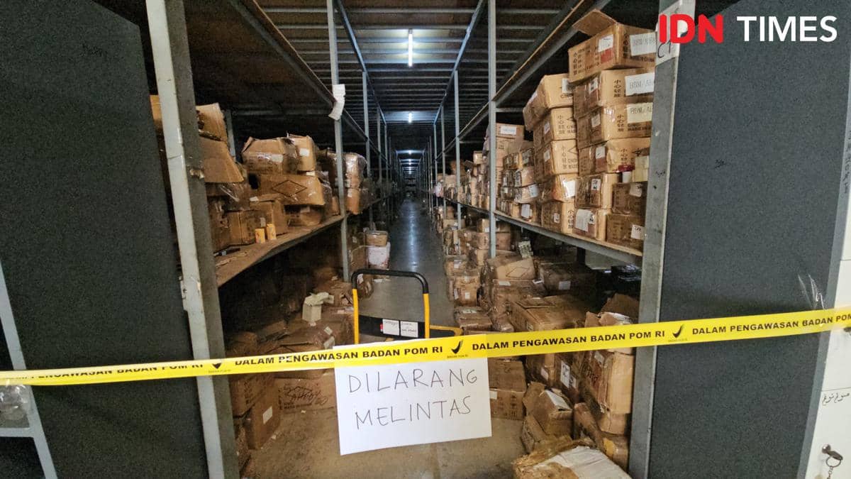 Gudang berisi tumpukan kardus kosmetik ilegal di Tangerang disegel dengan pita pengawasan BPOM dan tanda larangan melintas.