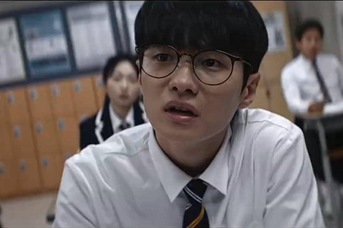 Seorang siswa berkacamata mengenakan seragam sekolah putih dan dasi sedang duduk di kelas dalam adegan serial Teach You a Lesson.