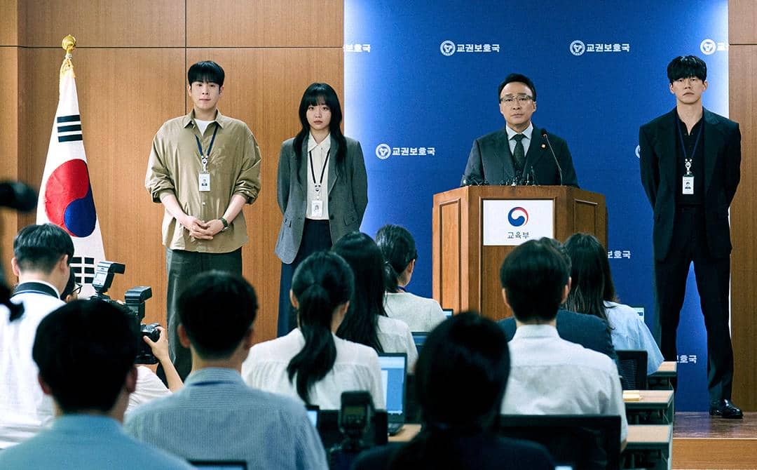Empat orang berdiri di depan podium saat konferensi pers dengan latar bendera Korea Selatan dan logo institusi pemerintah.