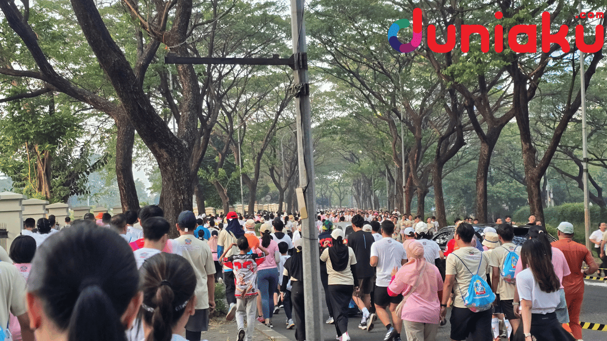 Peserta ONE PIECE Run 2026 berlari dan berjalan di jalan rindang dengan pepohonan besar di kedua sisi pada pagi hari.