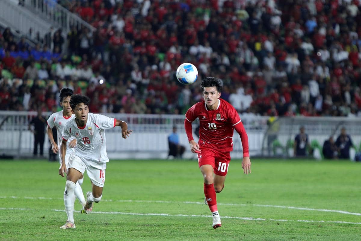 Pemain Timnas Indonesia U-19 mengenakan seragam merah berlari mengejar bola di lapangan saat pertandingan Piala AFF melawan tim lawan.