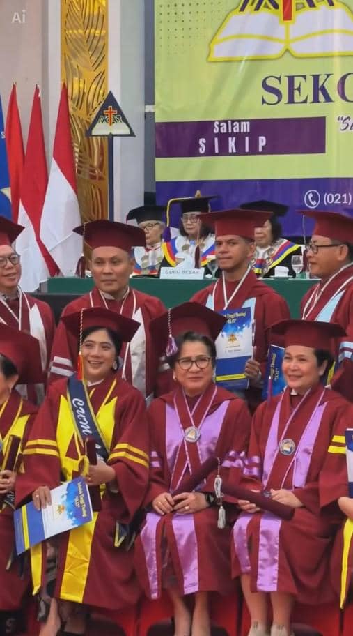 Beberapa wisudawan dan wisudawati mengenakan toga merah marun dengan selempang dan medali saat berfoto di acara wisuda di sebuah kampus.