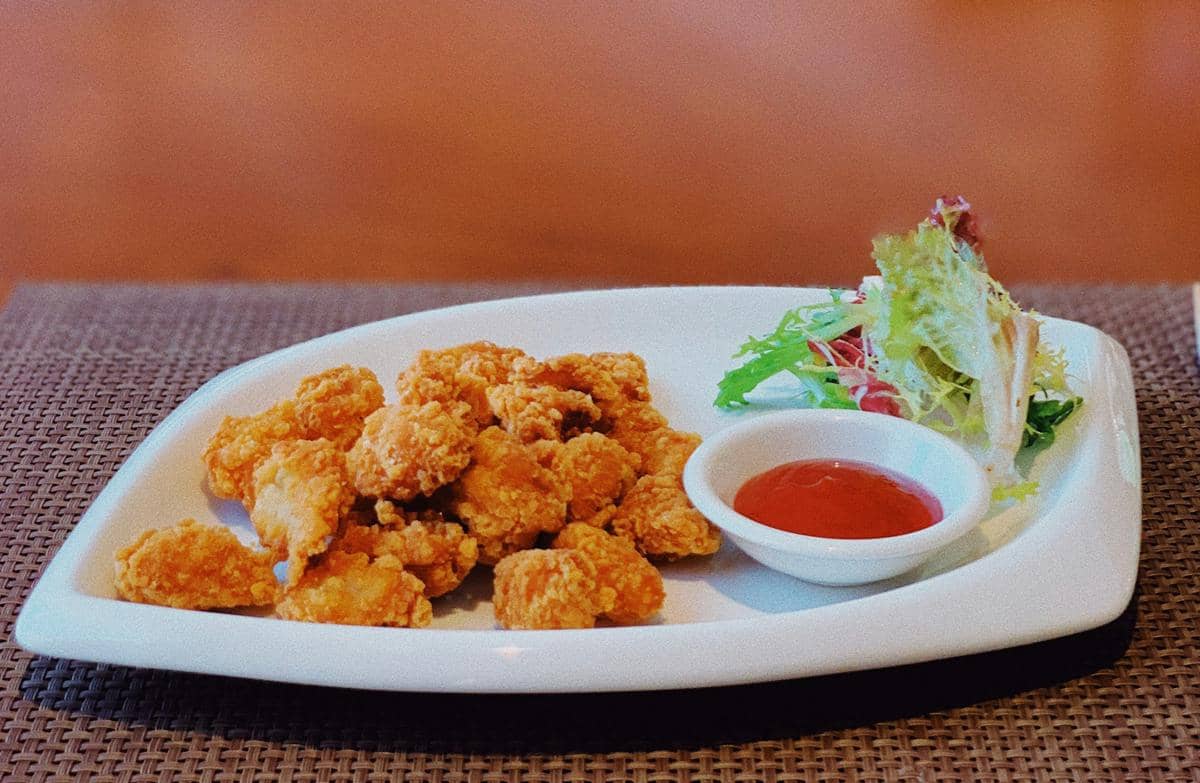 Semangkuk popcorn chicken berwarna keemasan dengan saus cocolan, ilustrasi makanan dari Unsplash oleh Hanxiao Xu.