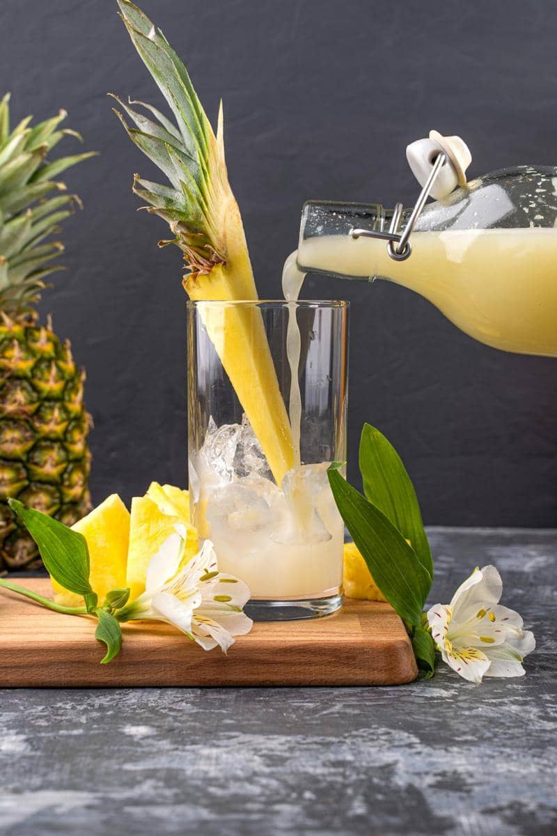 ilustrasi menuangkan jus nanas ke dalam gelas 