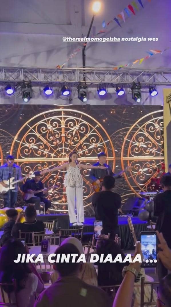 Seorang vokalis tampil bernyanyi di atas panggung bersama band Geisha di depan penonton yang menikmati pertunjukan musik.