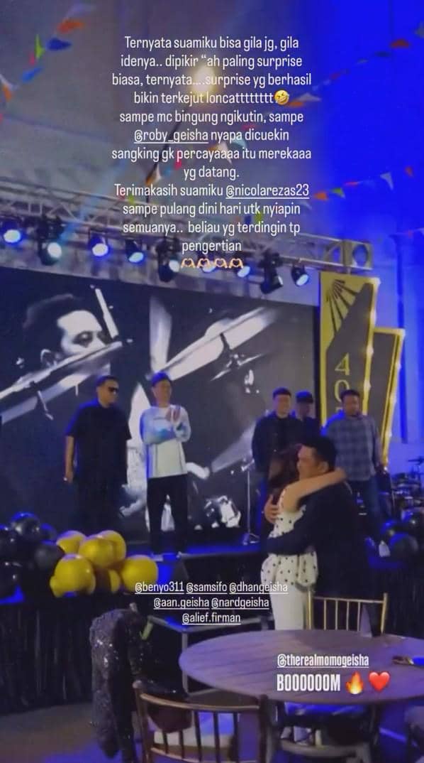 Momo memeluk seseorang di depan panggung saat tampil bersama band Geisha dalam sebuah acara dengan dekorasi balon hitam dan kuning.