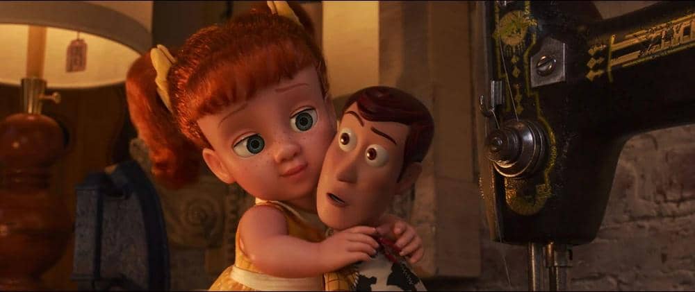 Boneka perempuan berambut merah memeluk karakter mainan koboi di dekat mesin jahit dalam adegan film animasi Toy Story 4.