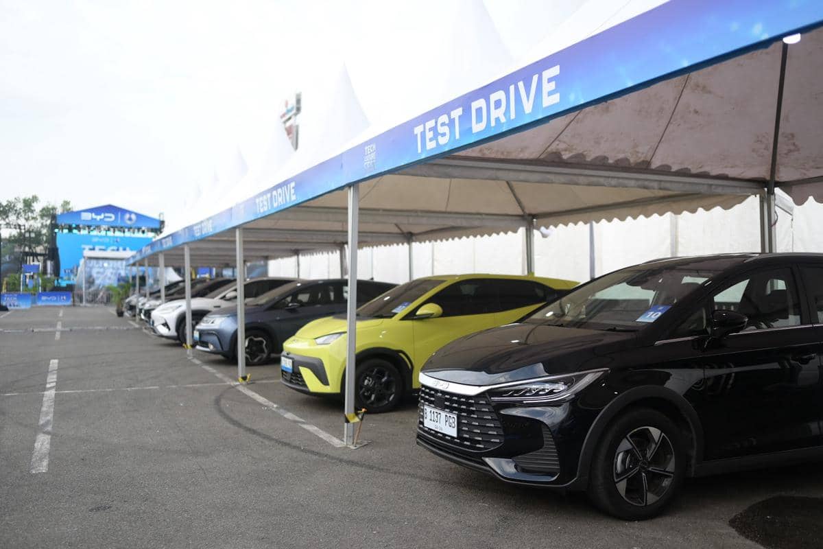 Deretan mobil listrik berbagai warna terparkir di area test drive yang dinaungi tenda putih dengan tulisan besar 'Test Drive'.