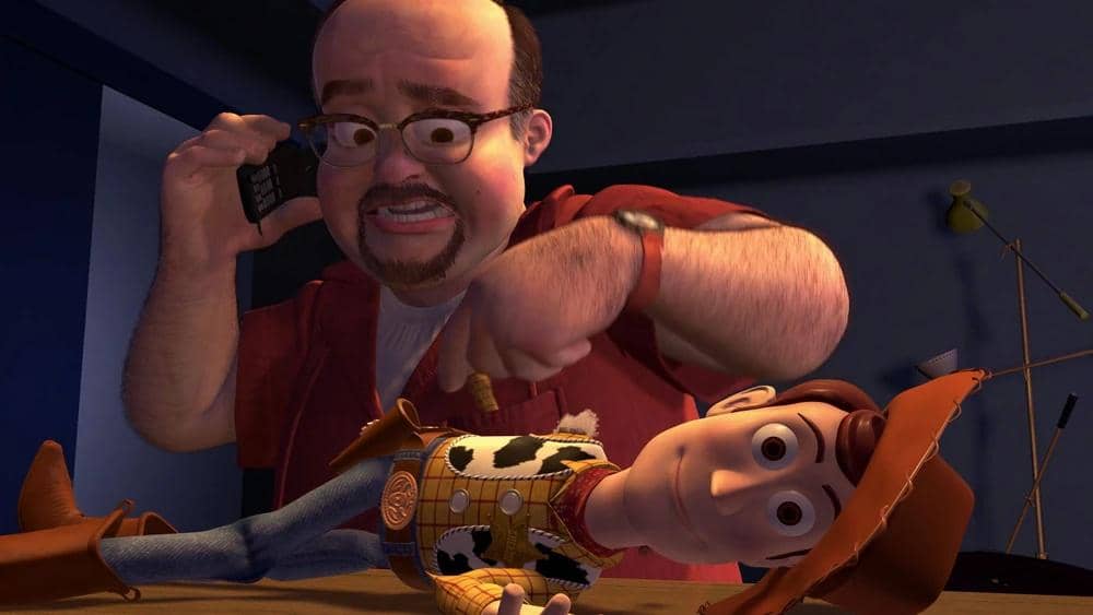 Tokoh pria berkacamata dalam film animasi Toy Story 2 sedang memperbaiki mainan koboi bernama Woody sambil berbicara di telepon.