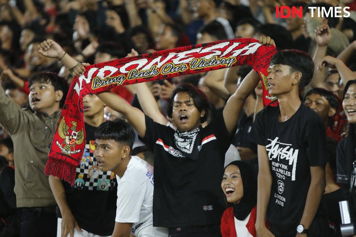 Suporter Timnas Indonesia U-19 bersorak dan mengibarkan syal merah bertuliskan dukungan di Stadion Utama Sumut saat laga kontra Vietnam.