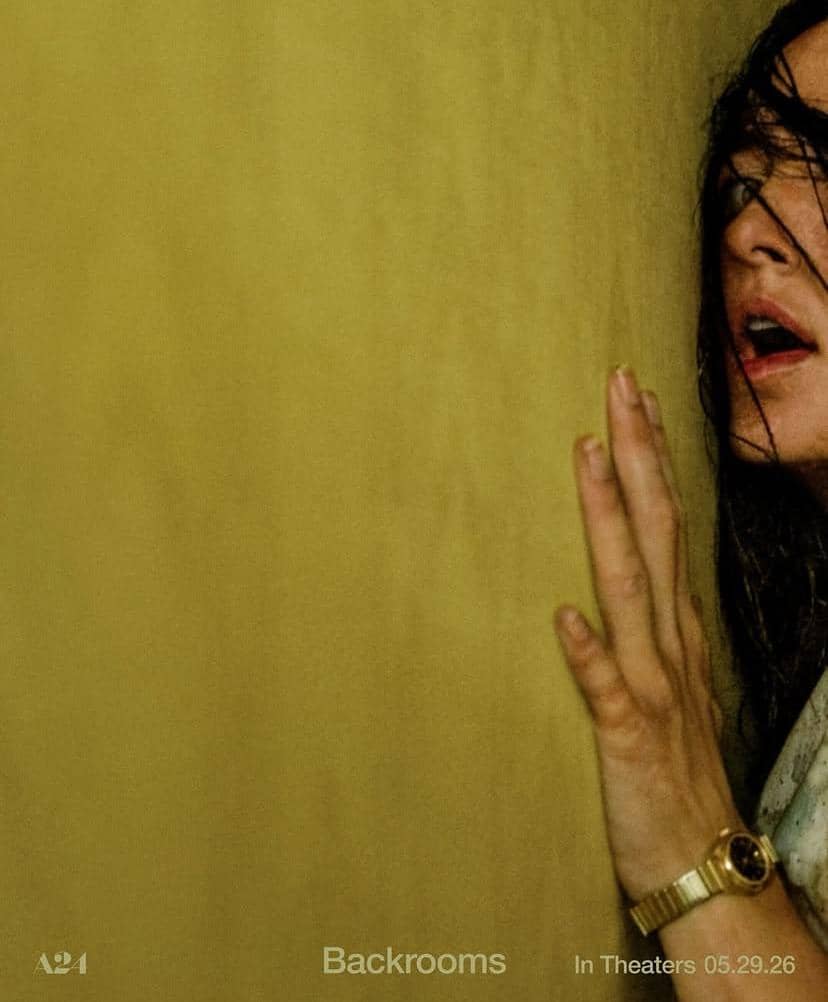 Seorang perempuan menyentuh dinding berwarna kuning dengan ekspresi tegang dalam poster film Backrooms produksi A24.