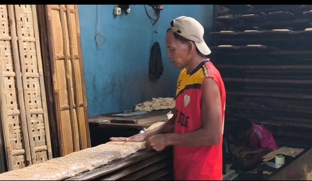 Seorang pengrajin tempe di Kabupaten Bogor sedang menata tempe yang dibungkus plastik di atas rak bambu di ruang produksi.