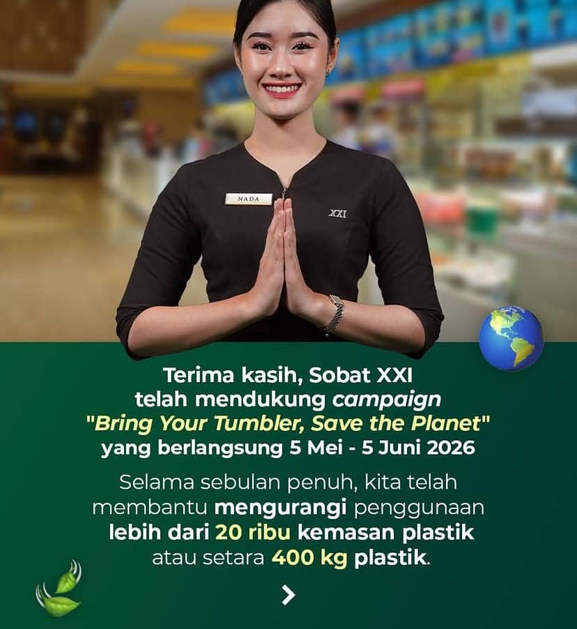 Seorang petugas Cinema XXI mengenakan seragam hitam dengan senyum ramah dan gestur salam, di latar belakang area bioskop yang terang.