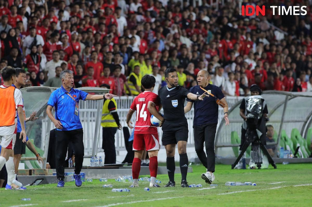 Wasit menghentikan pertandingan saat pemain Indonesia U-19 dan staf pelatih Vietnam berdebat di pinggir lapangan dengan latar suporter memenuhi stadion.