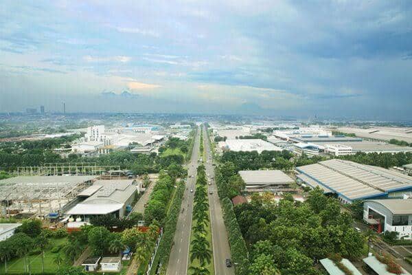 Pemandangan udara kawasan industri Cikarang dengan jalan utama lebar yang dikelilingi pepohonan dan bangunan pabrik di Bekasi.