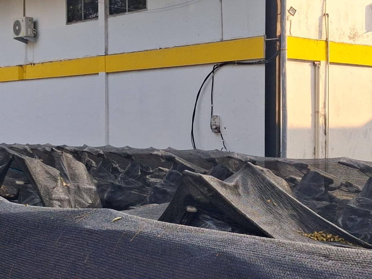 Ratusan motor terparkir di dalam gudang dengan seluruh bagian tertutup jaring hitam di depan dinding bercat putih dan kuning.