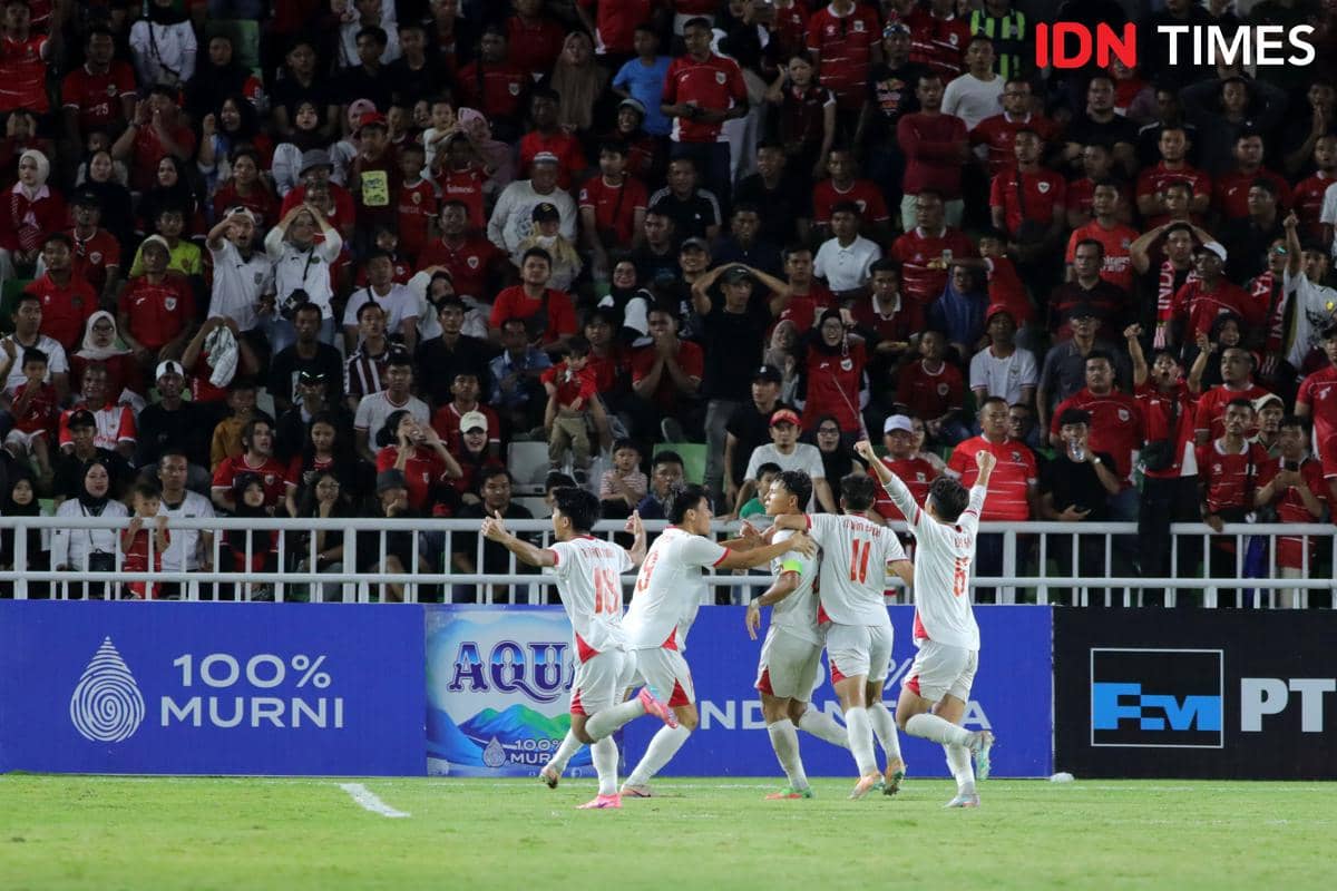 Pemain Vietnam U-19 merayakan gol ke gawang Indonesia U-19 di Stadion Utama Sumut dengan latar penonton berpakaian merah di tribun.