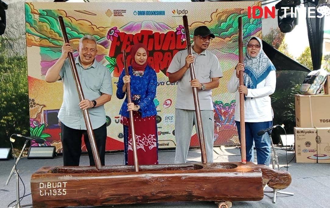 Empat orang memainkan lesung kayu besar dengan alu di atas panggung Festival Serayu, merepresentasikan alat musik tradisional Banyumas.