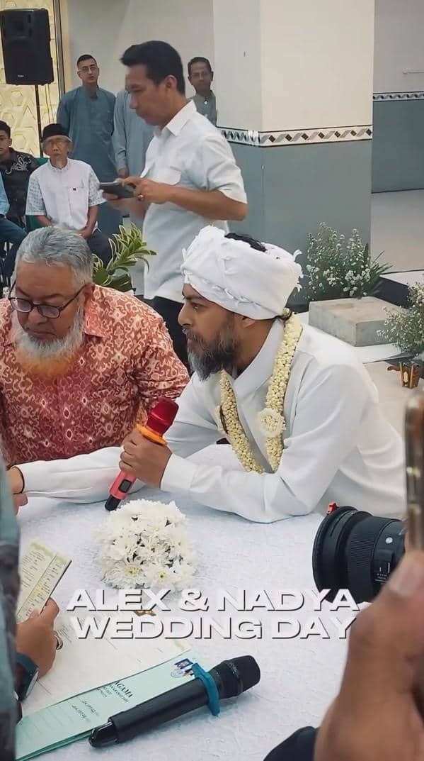 Seorang pria mengenakan busana putih dan sorban sedang melangsungkan akad nikah di hadapan saksi dan penghulu di sebuah ruangan.