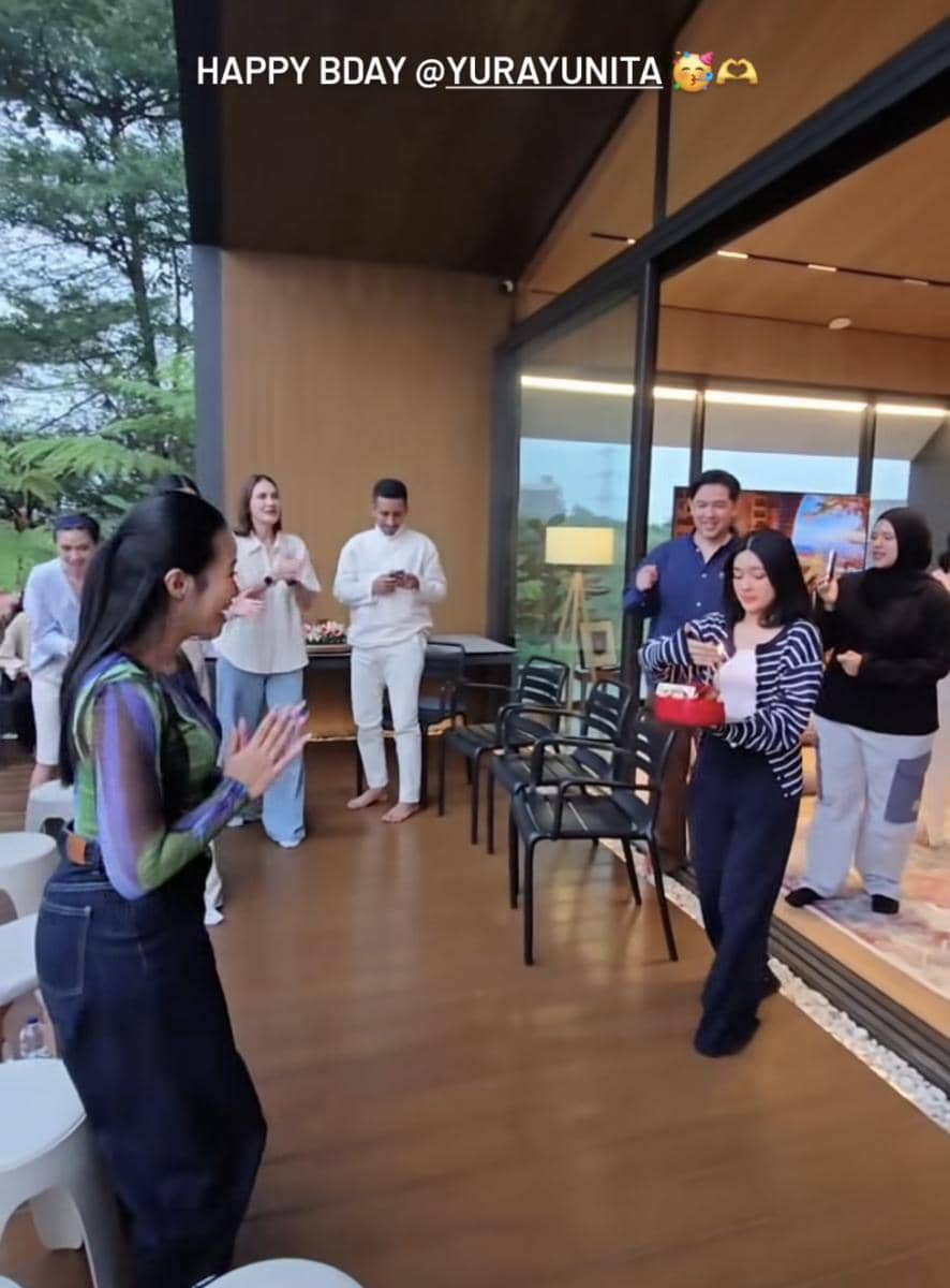 Sejumlah orang merayakan ulang tahun di teras rumah modern dengan suasana hangat, salah satu di antaranya membawa kue ulang tahun.