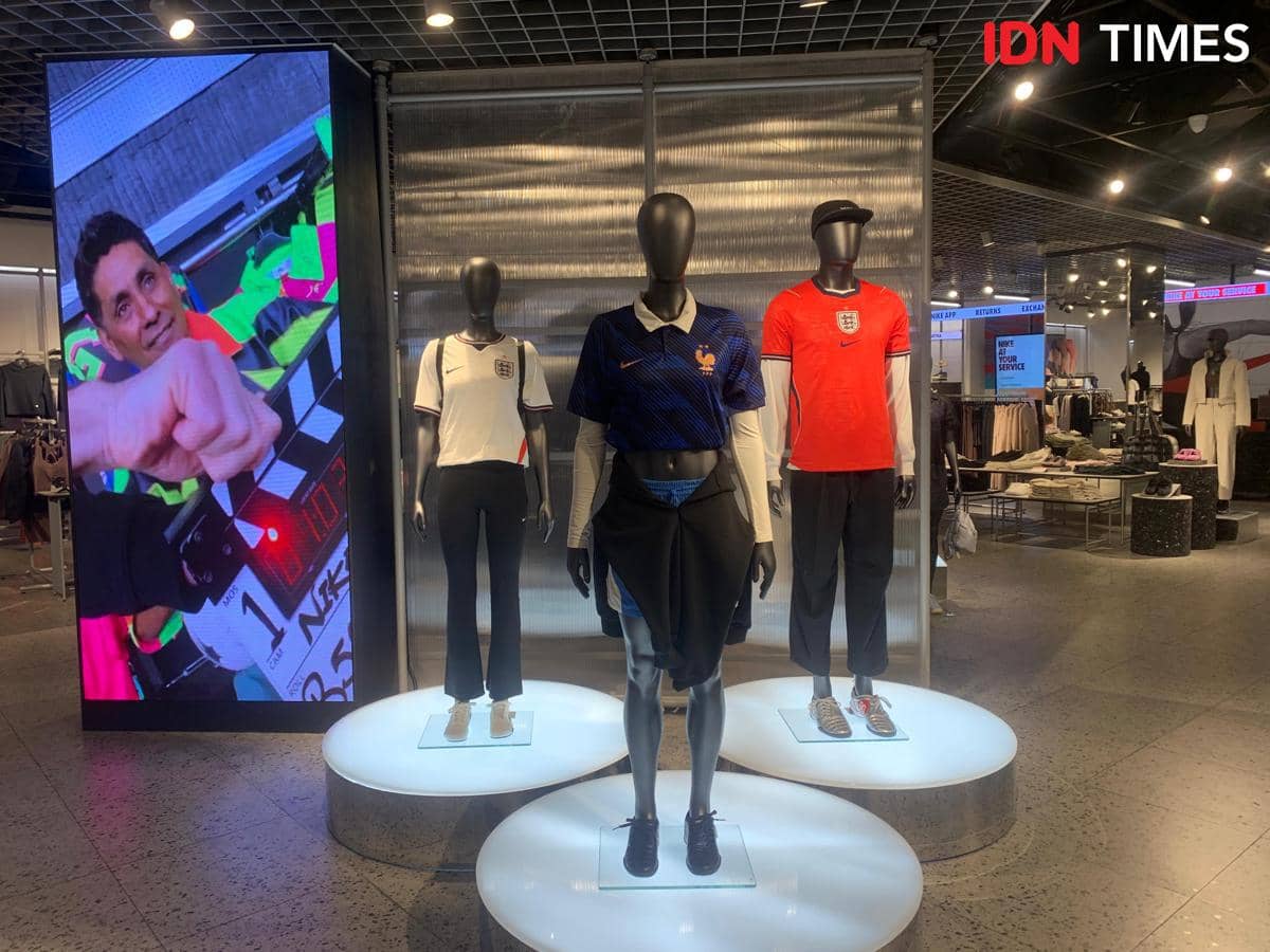 Manekin mengenakan jersey tim peserta Piala Dunia 2026 dipajang di toko pakaian di Medan dengan pencahayaan modern dan layar digital besar di belakangnya.