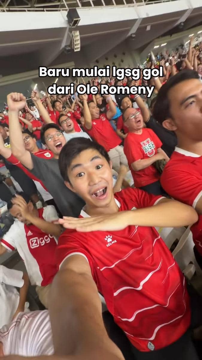 Penonton bersorak gembira di stadion Gelora Bung Karno mengenakan jersey merah saat pertandingan timnas Indonesia melawan Mozambik.