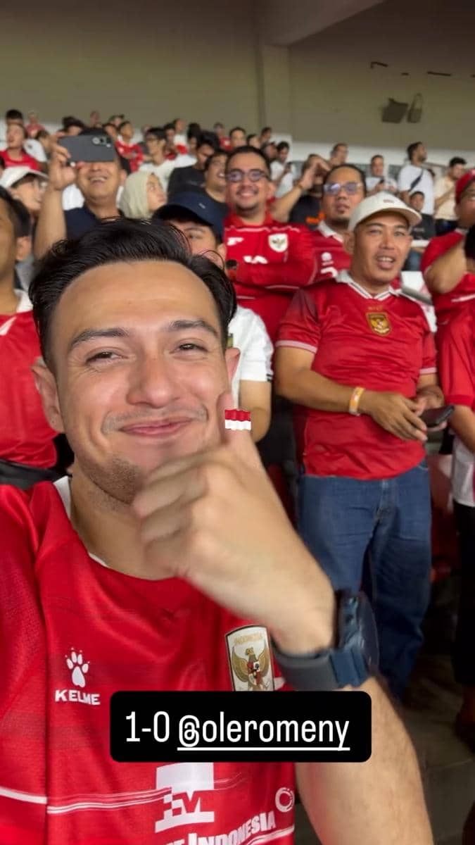 Seorang penonton mengenakan jersey timnas Indonesia tersenyum sambil mengacungkan jempol di tribun stadion GBK saat laga melawan Mozambik.