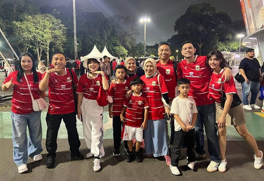 Sekelompok orang mengenakan jersey merah timnas Indonesia berpose bersama di luar Stadion GBK sebelum pertandingan melawan Mozambik.