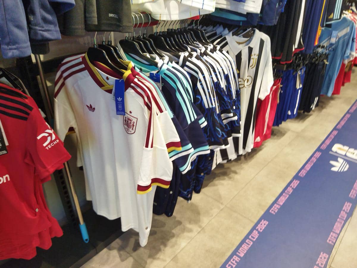 Deretan jersey tim peserta Piala Dunia 2026 berbagai warna dan desain tergantung rapi di rak toko olahraga di Medan.