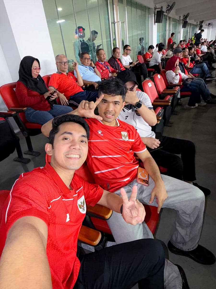 Penonton mengenakan jersey merah timnas Indonesia berpose di tribun Stadion GBK saat pertandingan melawan Mozambik.