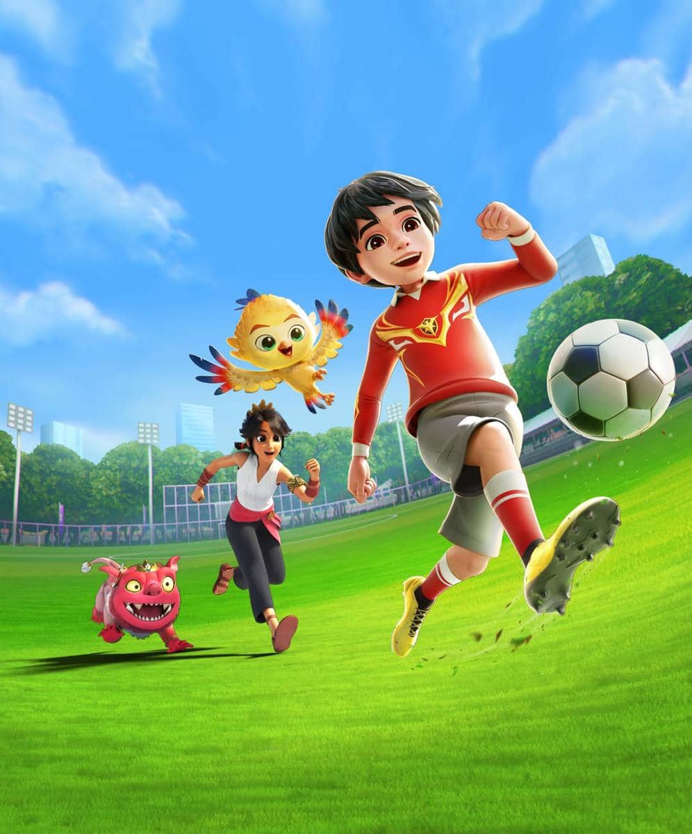 Karakter animasi anak dengan seragam merah menendang bola di lapangan hijau, diikuti teman dan makhluk lucu berwarna cerah di bawah langit biru.