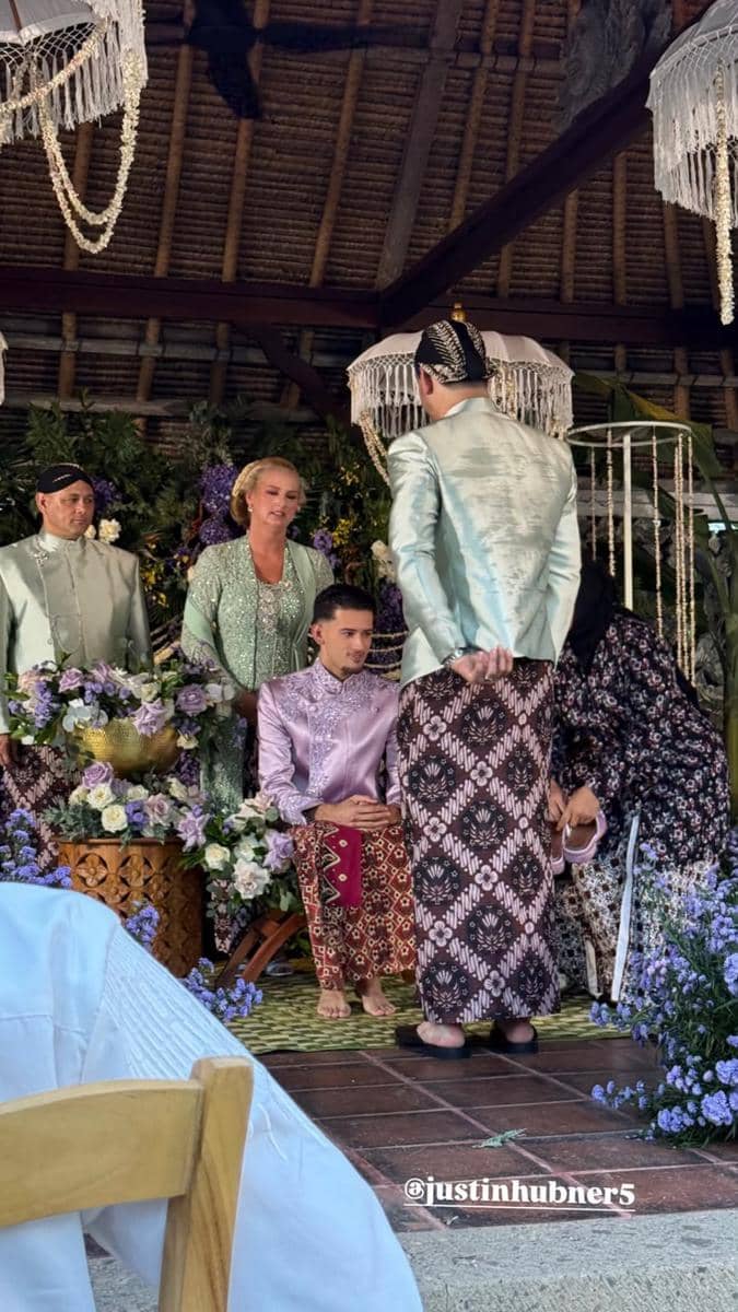 Suasana pengajian dan siraman dengan para tamu mengenakan busana adat Jawa berwarna pastel di bawah dekorasi bunga dan payung gantung.