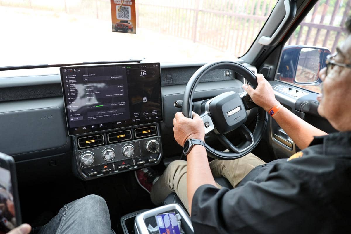 Pengemudi mengendarai mobil iCAR V23 dengan interior modern, layar sentuh besar di dashboard, dan setir berdesain futuristik.