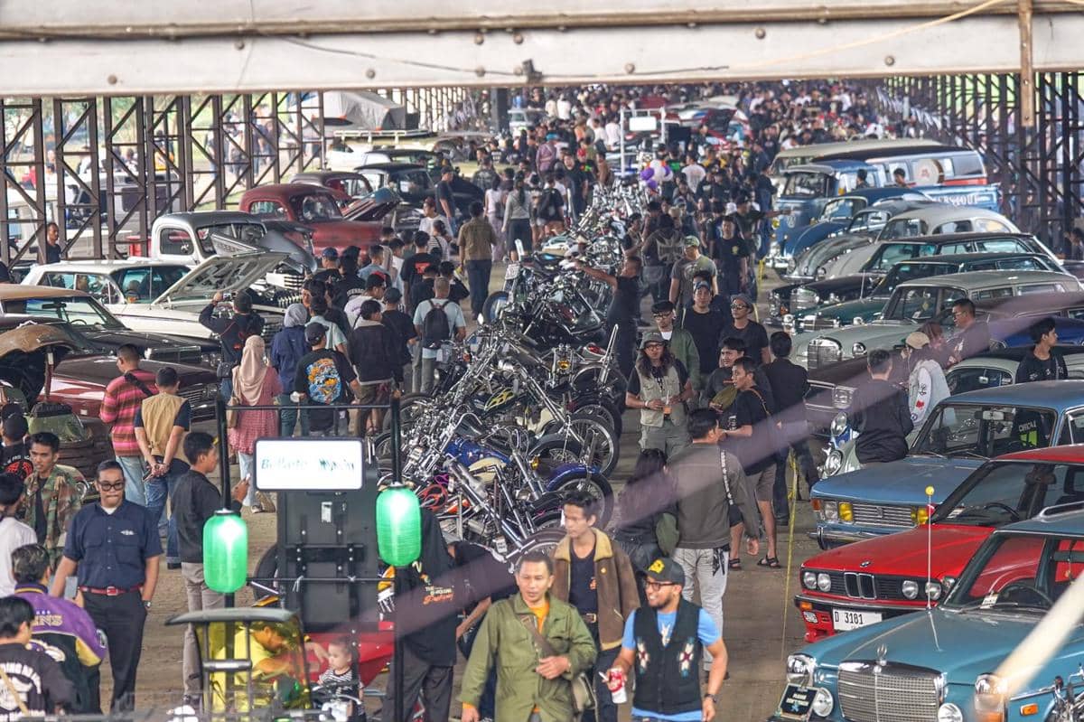 Kerumunan pengunjung menghadiri acara BBQ Ride ke-13 dengan deretan motor kustom dan mobil klasik di area pameran terbuka.