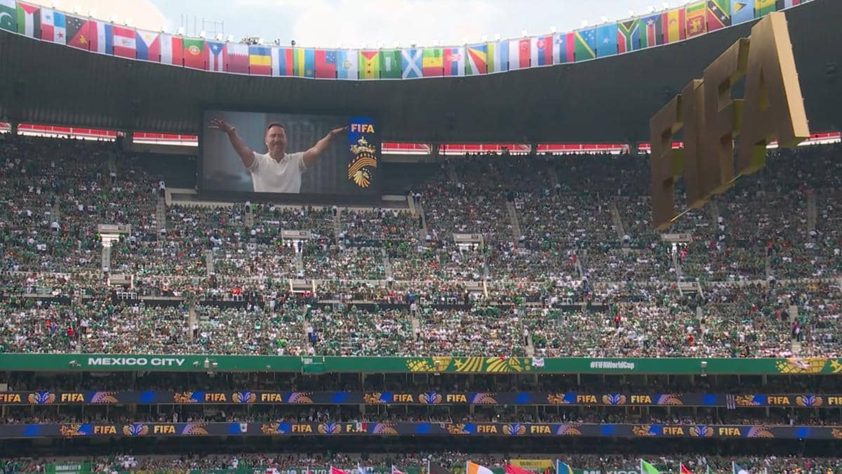 Stadion penuh penonton di Mexico City dengan layar besar menampilkan penampilan pembuka Piala Dunia 2026 dan logo FIFA berwarna emas.