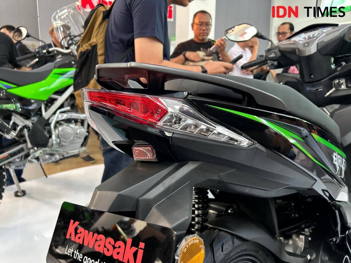 Tampak dekat lampu rem dan sein belakang motor Brusky 125 berwarna hitam dengan aksen hijau di area pameran kendaraan.