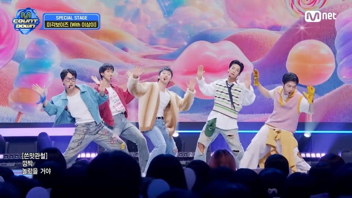 Lima anggota Migak Boys menari energik di panggung M Countdown dengan latar warna-warni bertema permen pada 11 Juni 2026.
