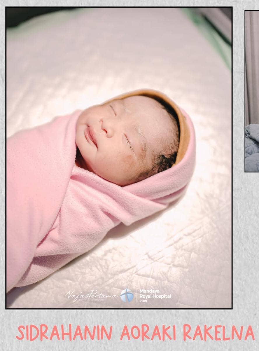 Bayi baru lahir dibedong dengan selimut berwarna merah muda sedang tertidur di atas alas putih di rumah sakit.