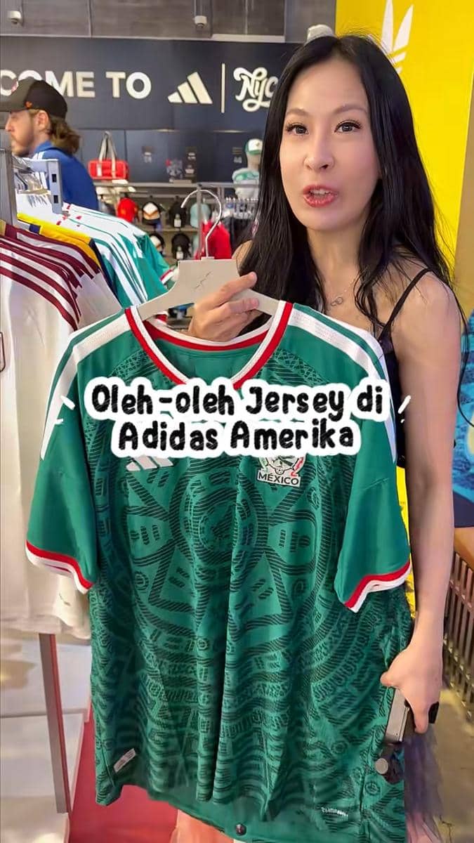 Seorang wanita memegang jersey tim nasional Meksiko berwarna hijau di toko Adidas Amerika Serikat sebagai oleh-oleh saat Piala Dunia 2026.