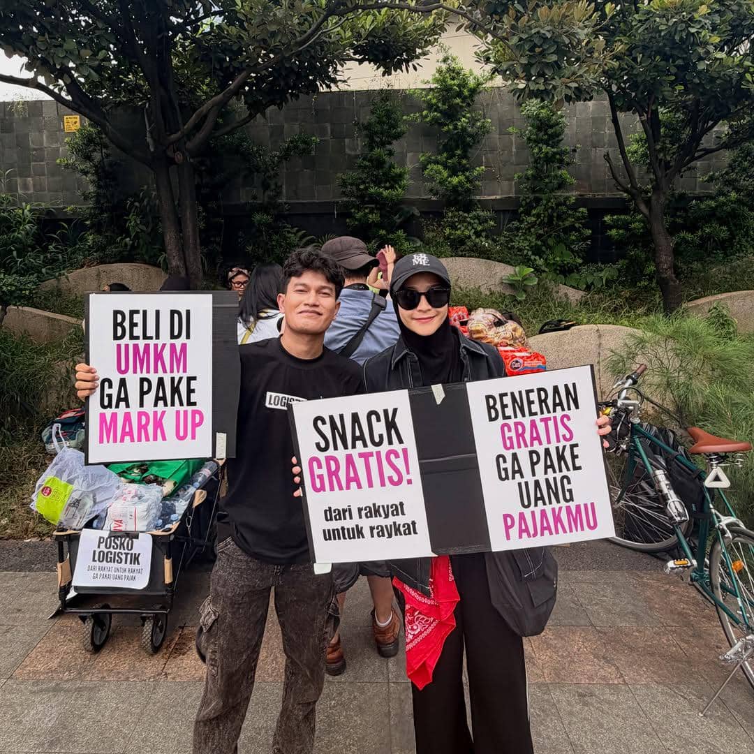 Dua orang memegang poster bertuliskan dukungan untuk UMKM dan pembagian makanan gratis saat aksi di kawasan Bundaran HI Jakarta.
