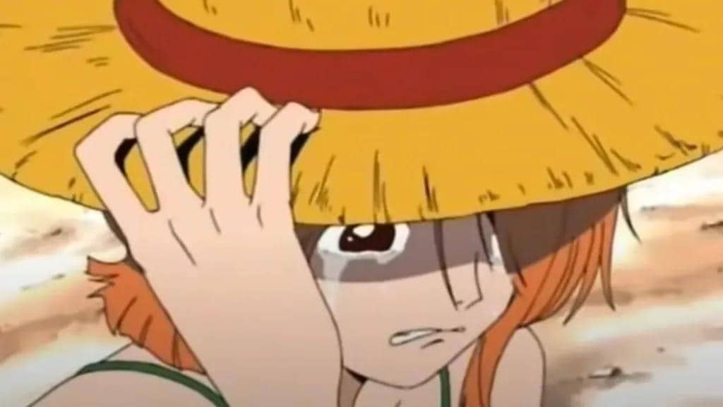 Nami menangis sambil mengenakan topi jerami milik Luffy di adegan anime One Piece, memperlihatkan ekspresi sedih dan putus asa.