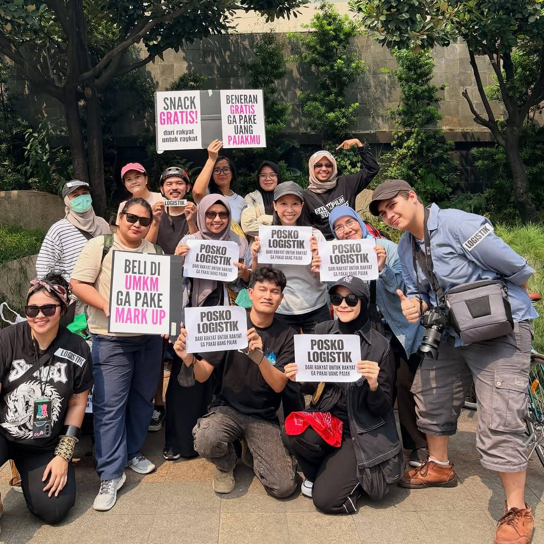 Sekelompok orang berpose sambil memegang poster bertuliskan dukungan untuk UMKM dan logistik rakyat saat aksi di kawasan Bundaran HI.
