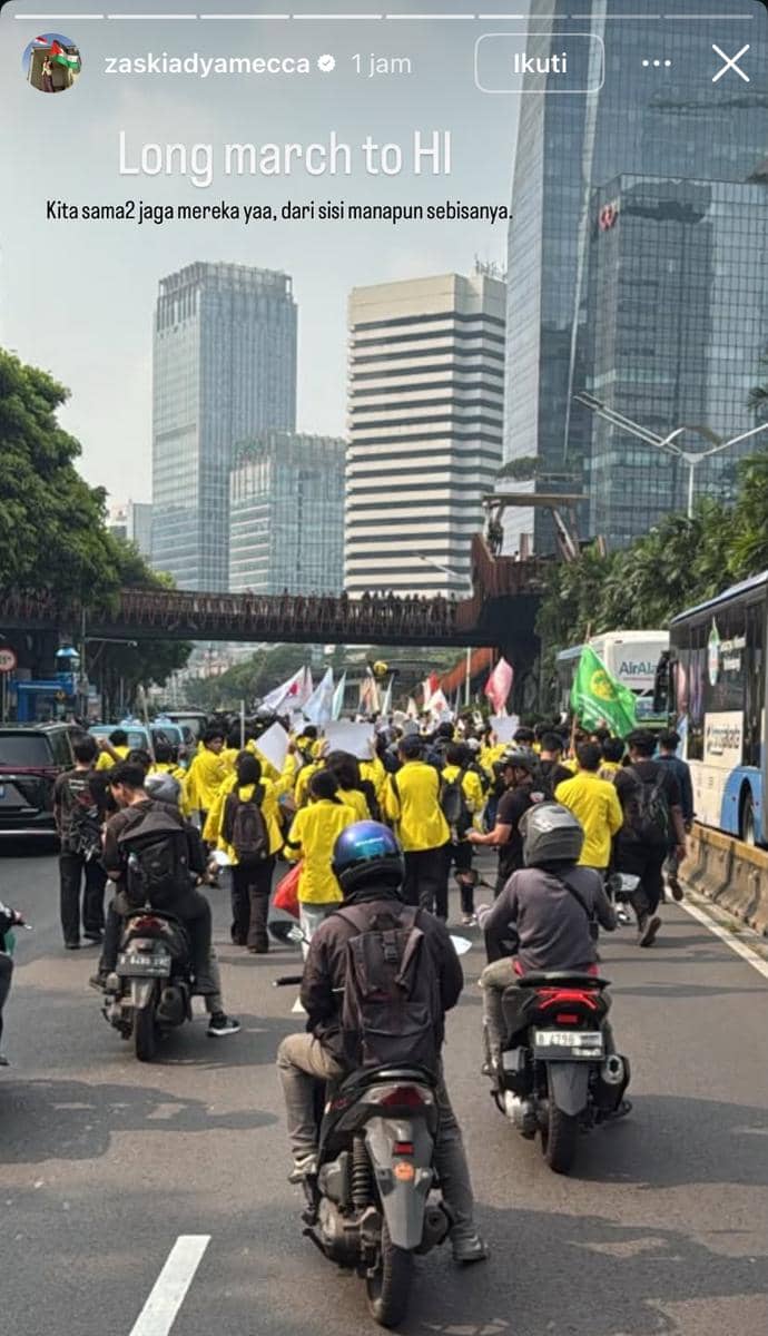 Sejumlah peserta demo mengenakan jaket kuning berjalan di kawasan Bundaran HI Jakarta, diiringi pengendara motor di jalan raya.